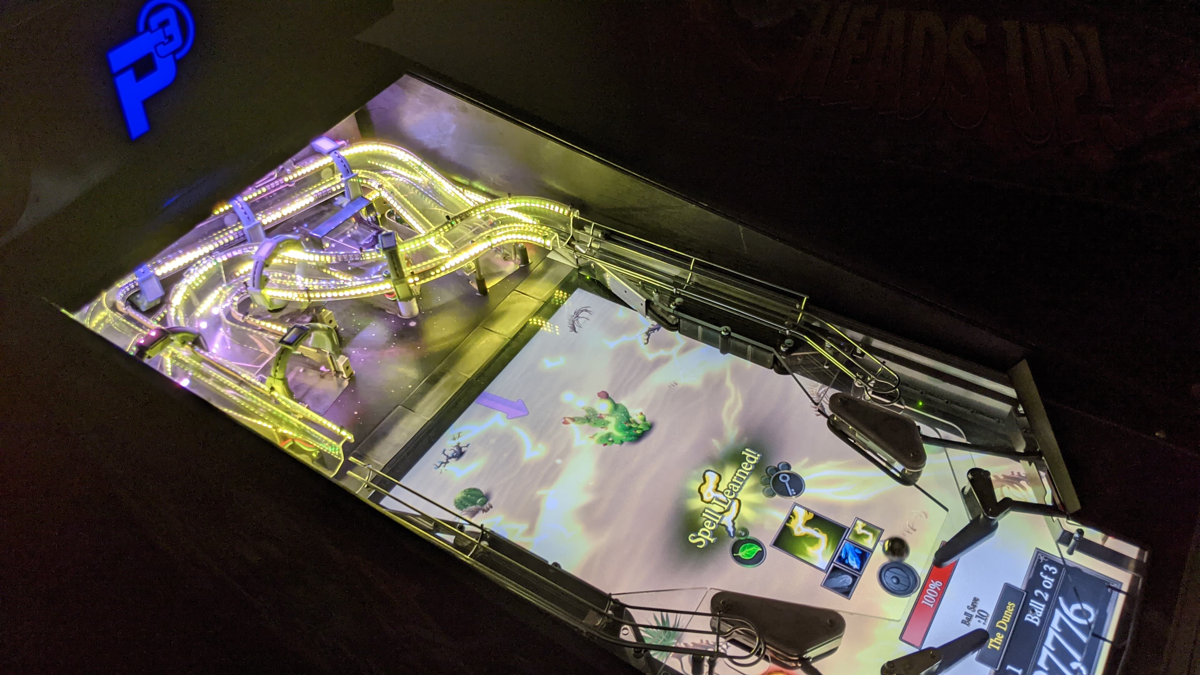 Illuminated pinball machine with colorful tracks and fantasy game screen