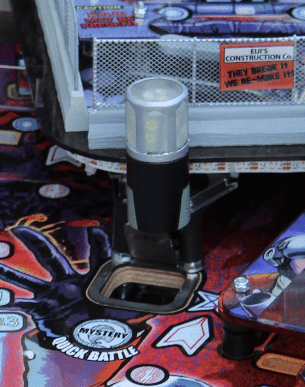 LED flashlight on colorful pinball machine with construction sign background