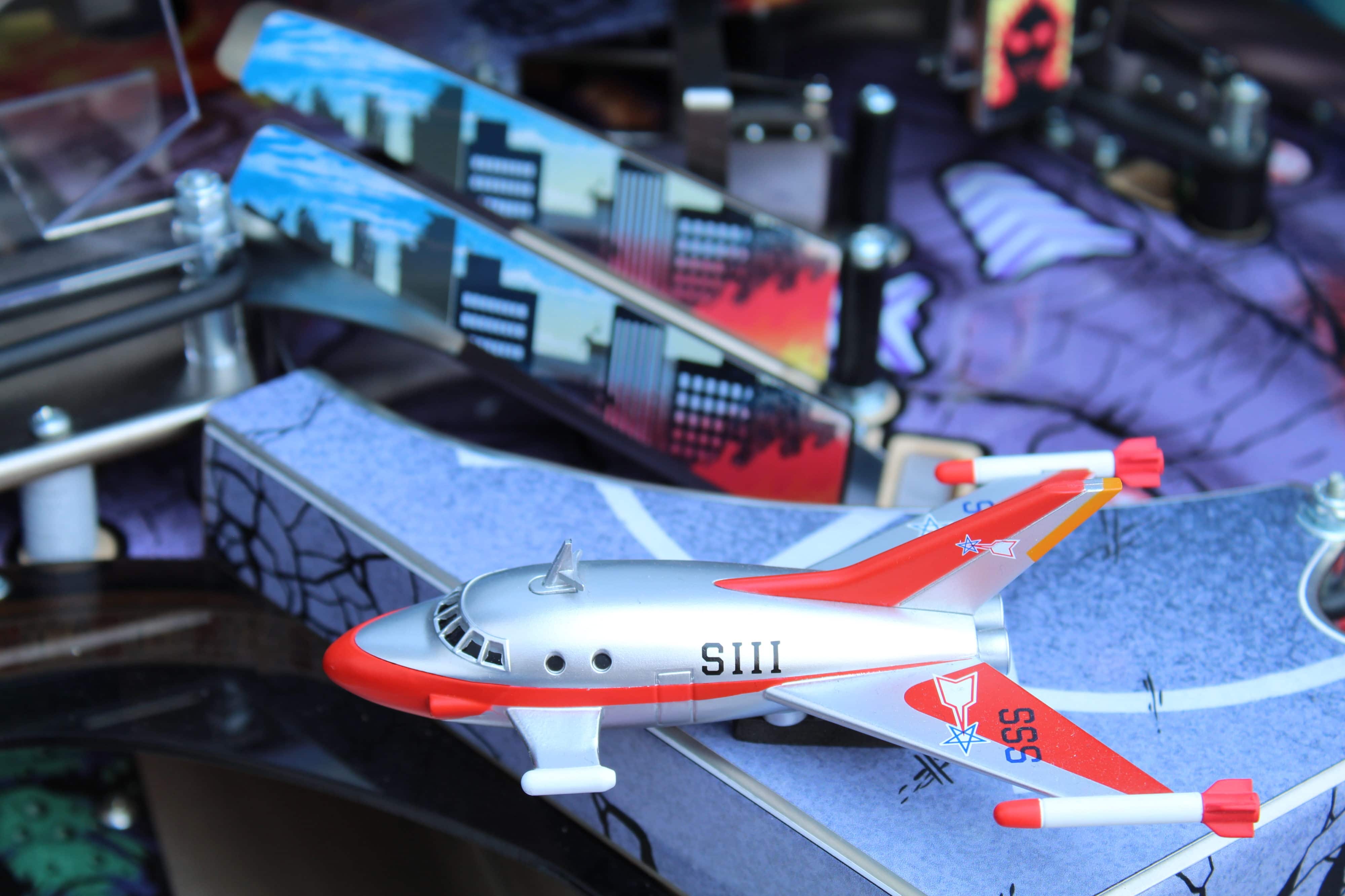 Vintage silver and red toy airplane model with city skyline background