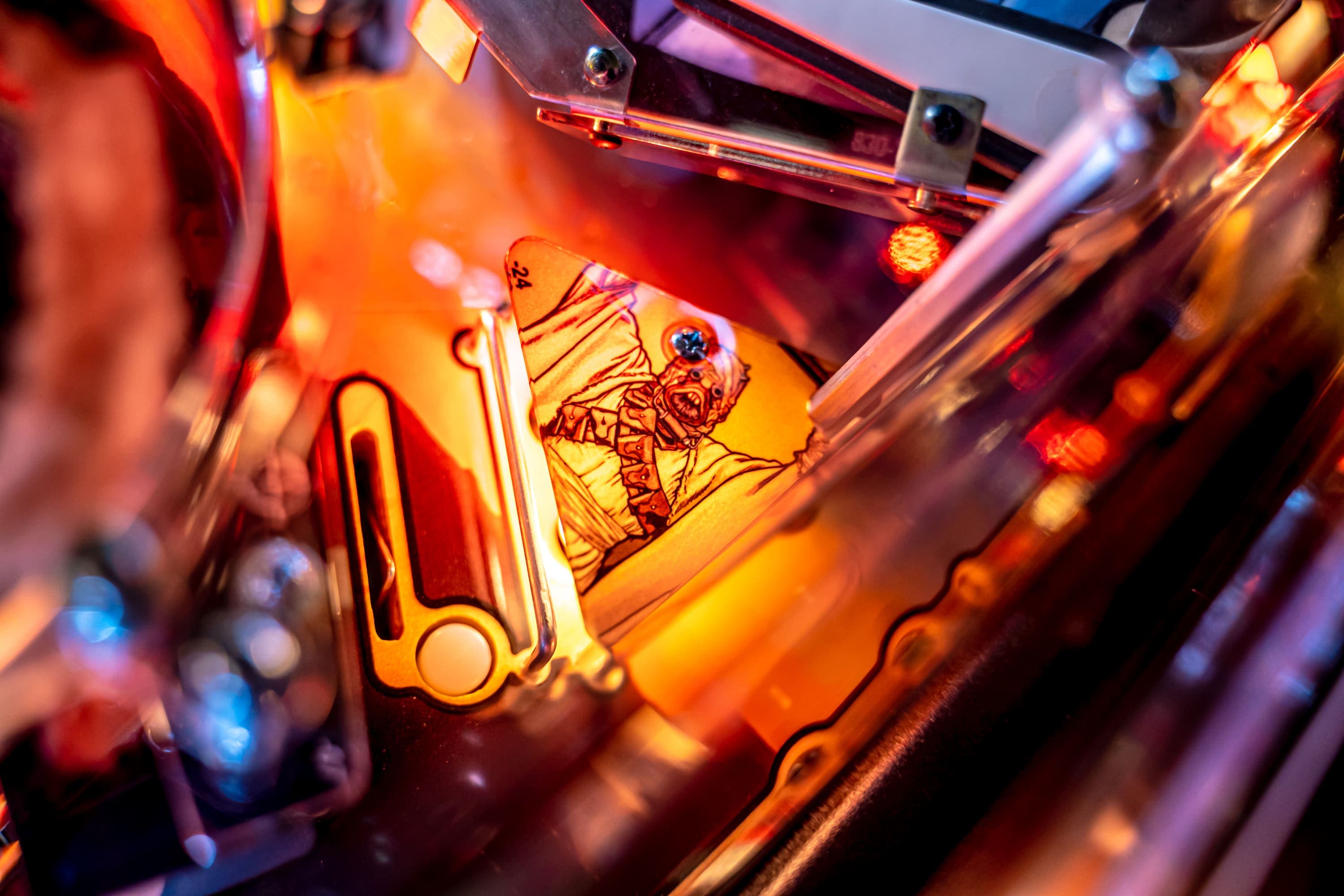 Pinball machine detail with illuminated monster character in warm colors
