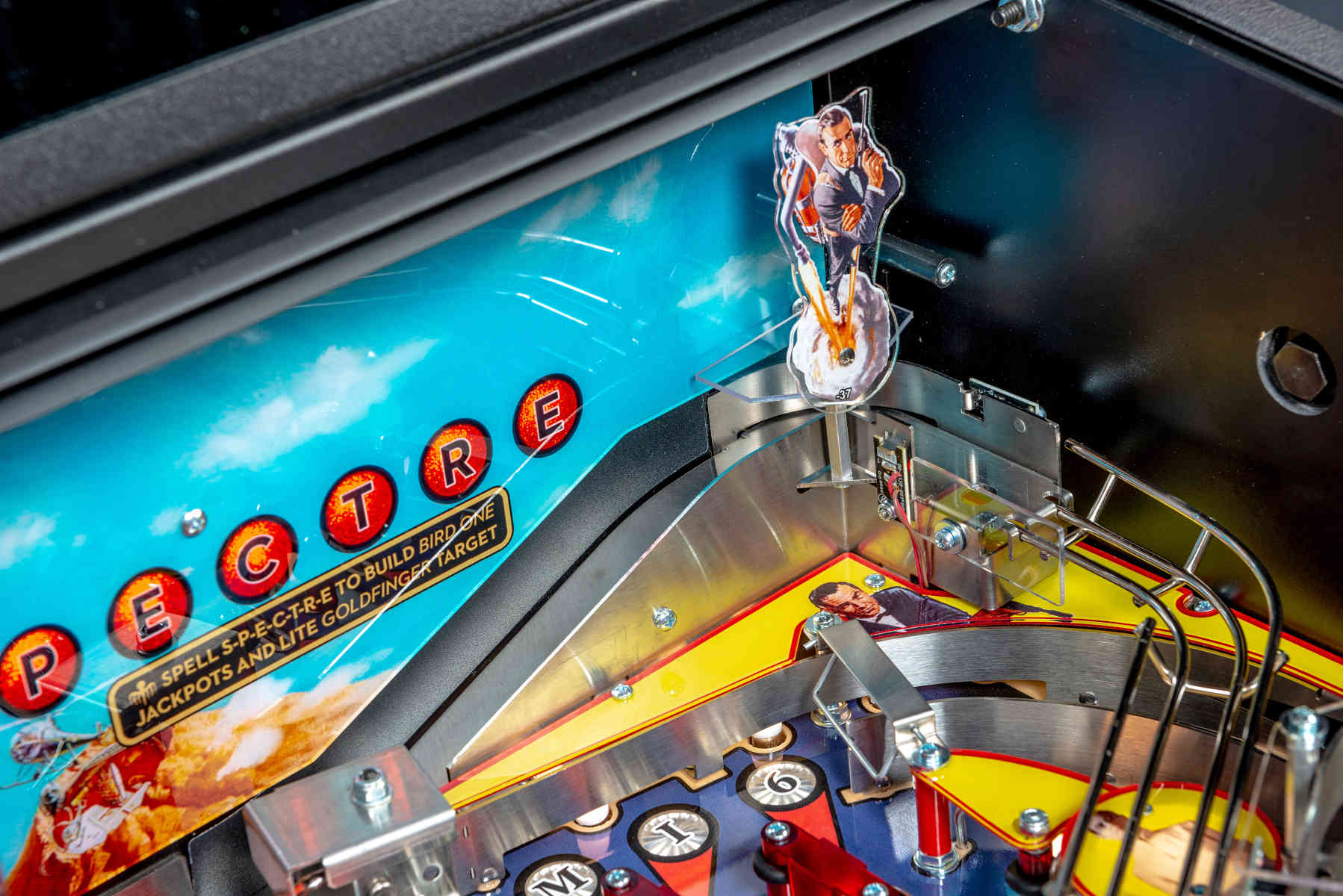 Closeup of a colorful pinball machine with 'SPECTRE' letters and figurines