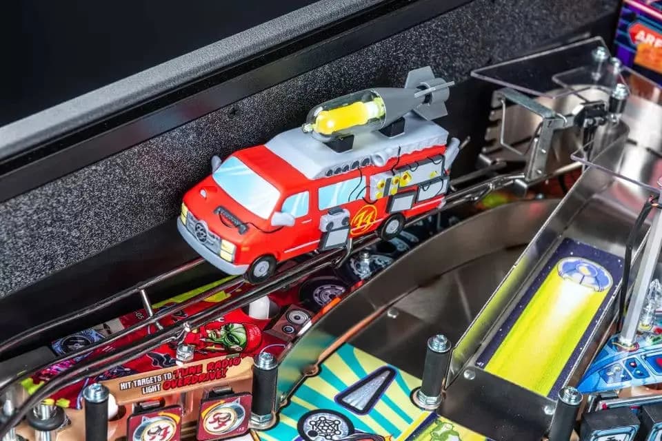 Red and white toy fire truck on a colorful pinball machine playfield