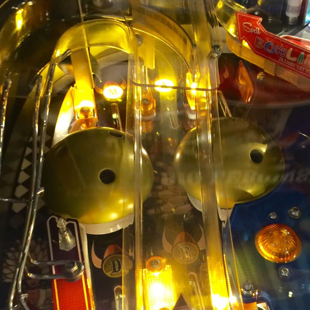 Glowing yellow bowling pins and balls inside illuminated pinball machine