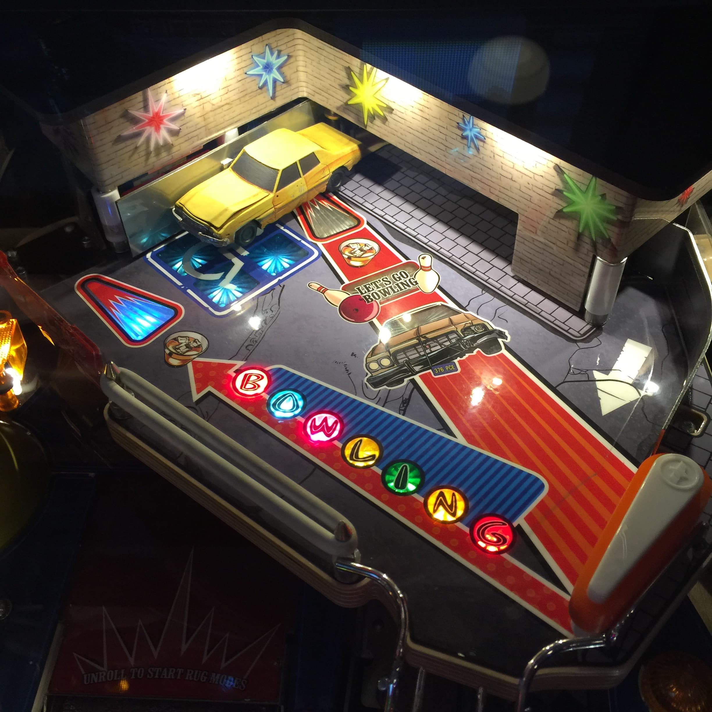 Vintage pinball machine with colorful lights and retro cars