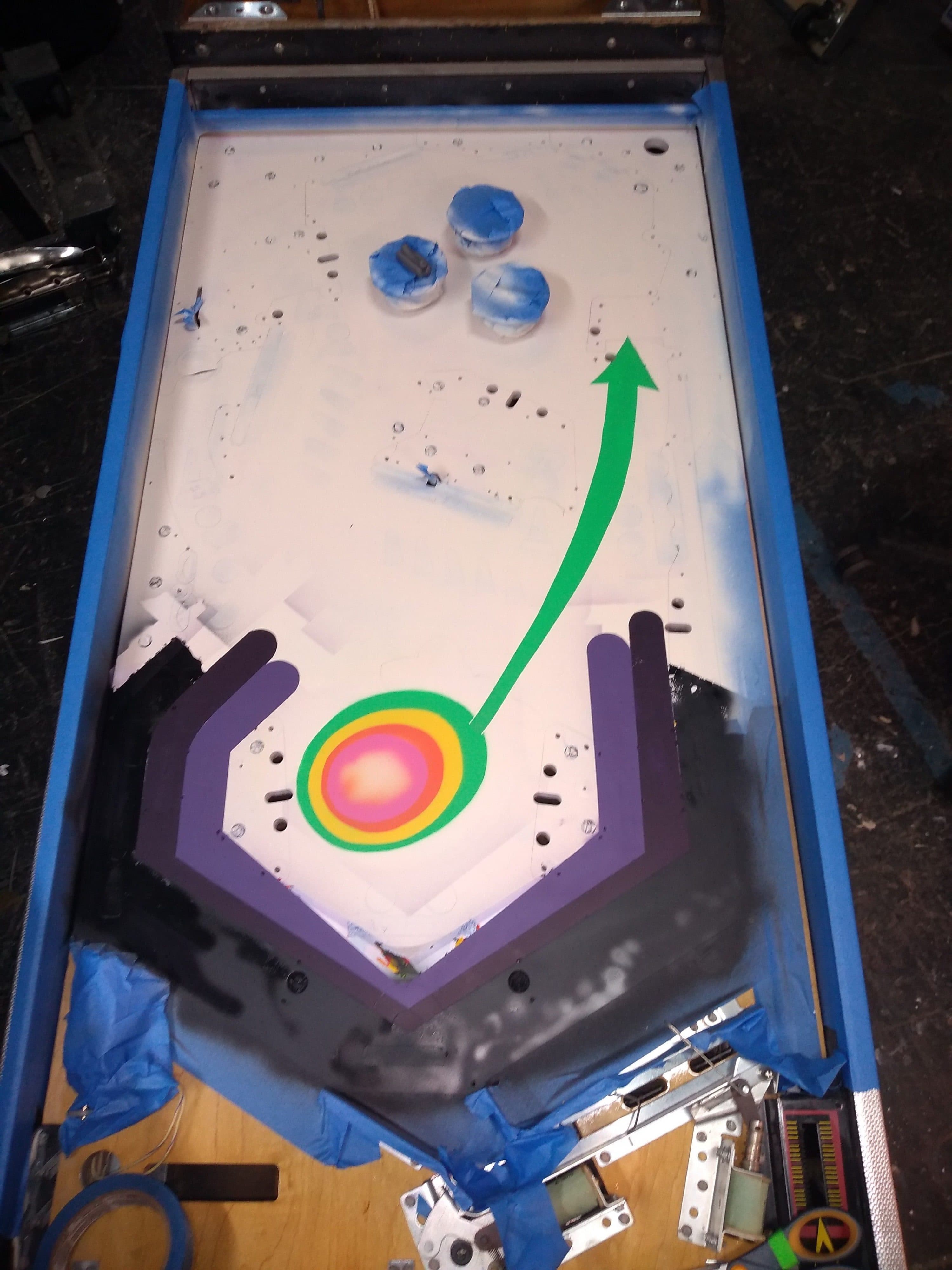 Pinball machine playfield with blue bumpers and colorful target zone