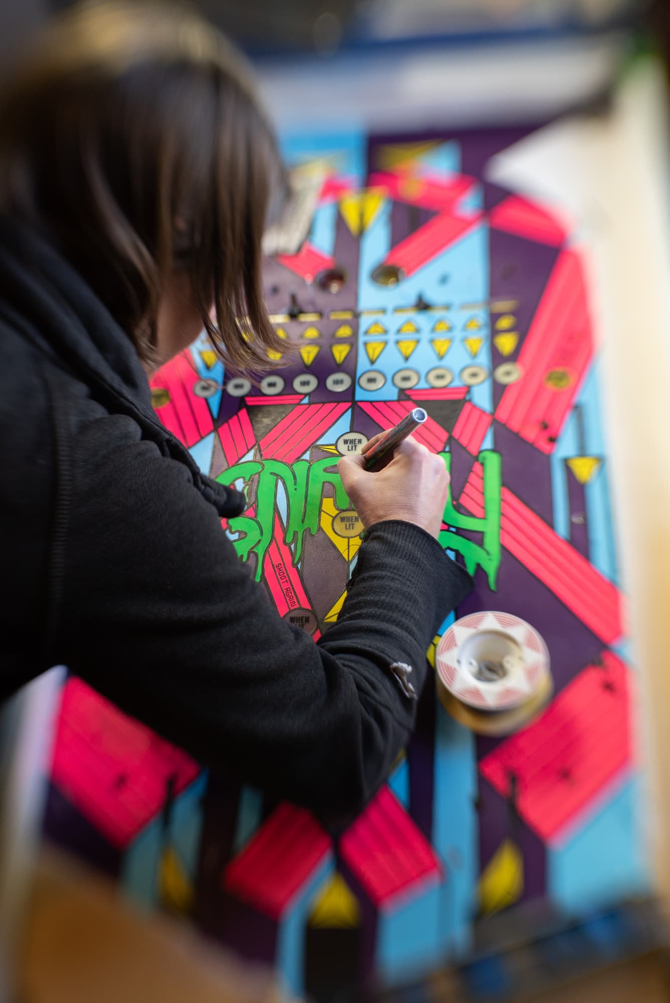 Artist drawing on colorful geometric street art with tape and marker