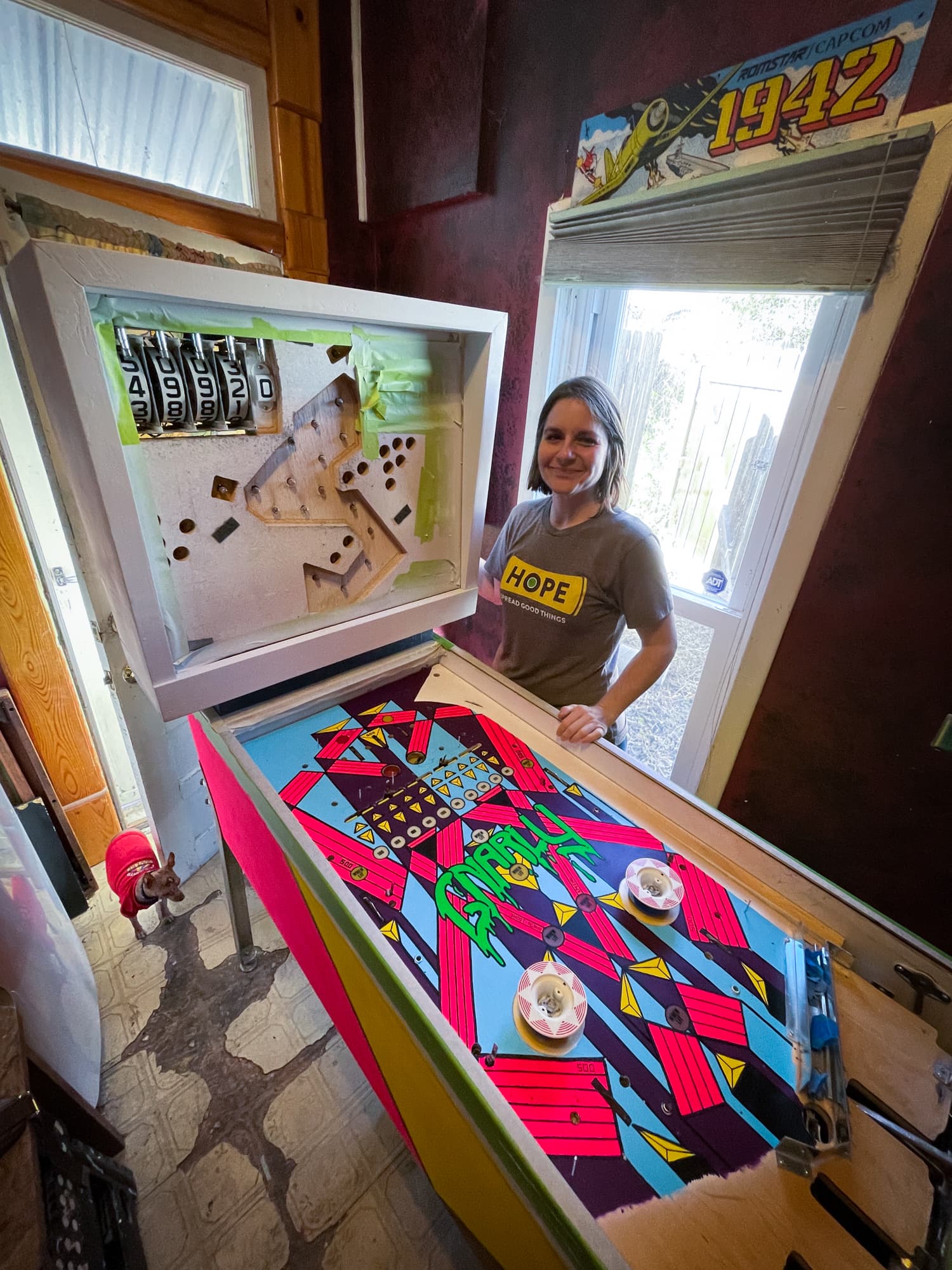 Custom pinball machine with colorful playfield and person standing nearby