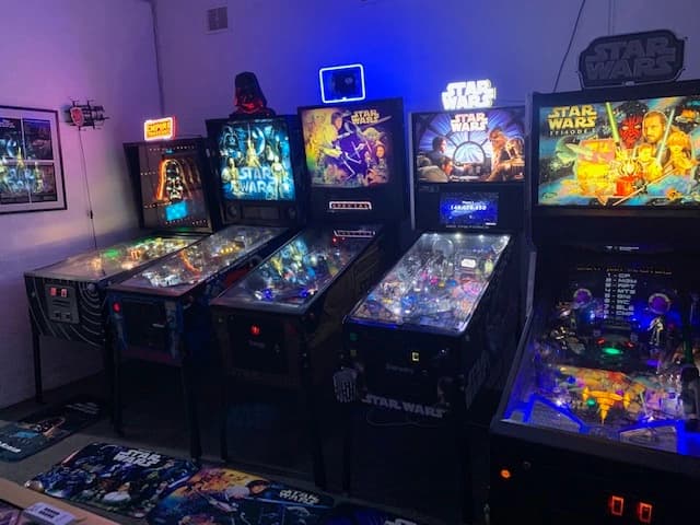 Star Wars pinball machines lined up in a dimly lit arcade room