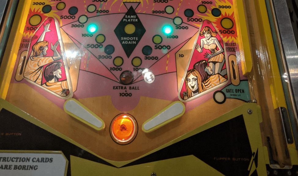 Vintage pinball machine with colorful artwork and glowing scoring lights