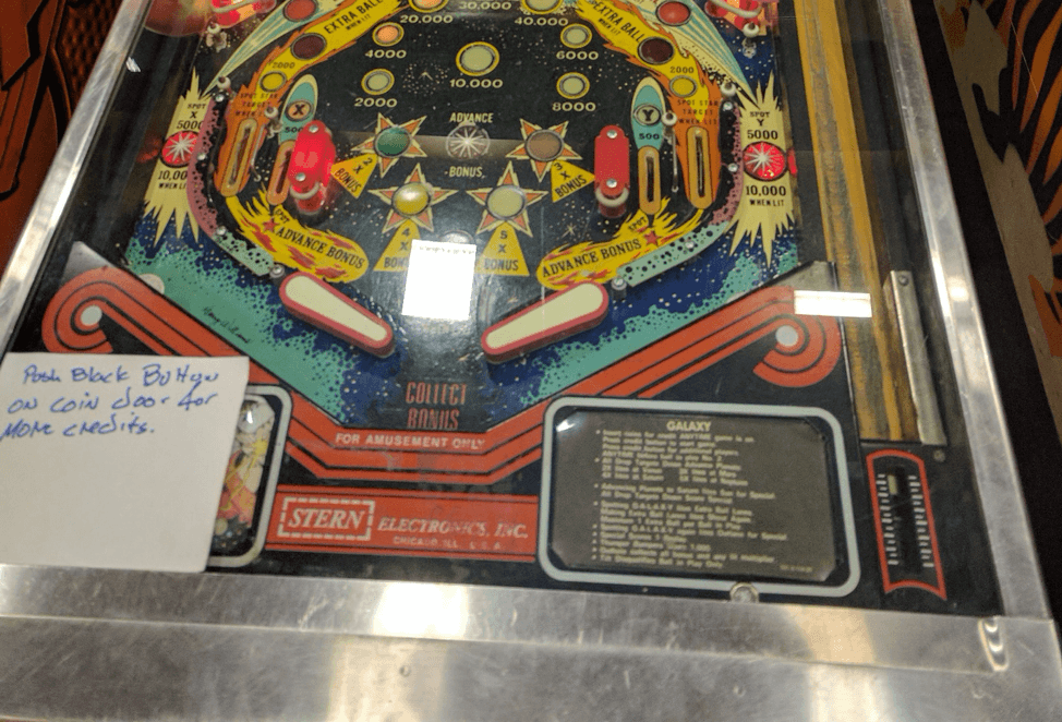 Vintage pinball machine playfield with colorful scoring zones and bumpers