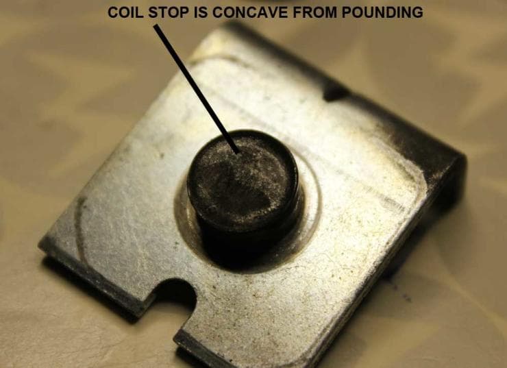 Concave metal coil stop on a textured mechanical component