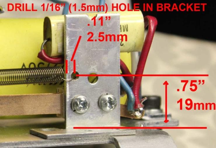 Metal bracket with drilled hole and measurements, showing electrical wiring connections